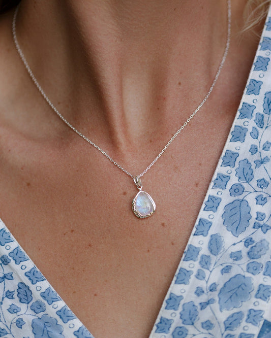 Sterling Silver 7 14 carat Yellow Gold Detailed Rainbow Moonstone Droplet Pendant Necklace worn by a person in a floral dress.