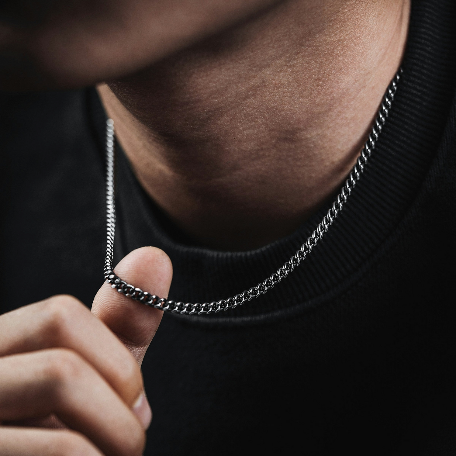 close-up of a ginger-bearded man with a silver chain against a black T-shirt