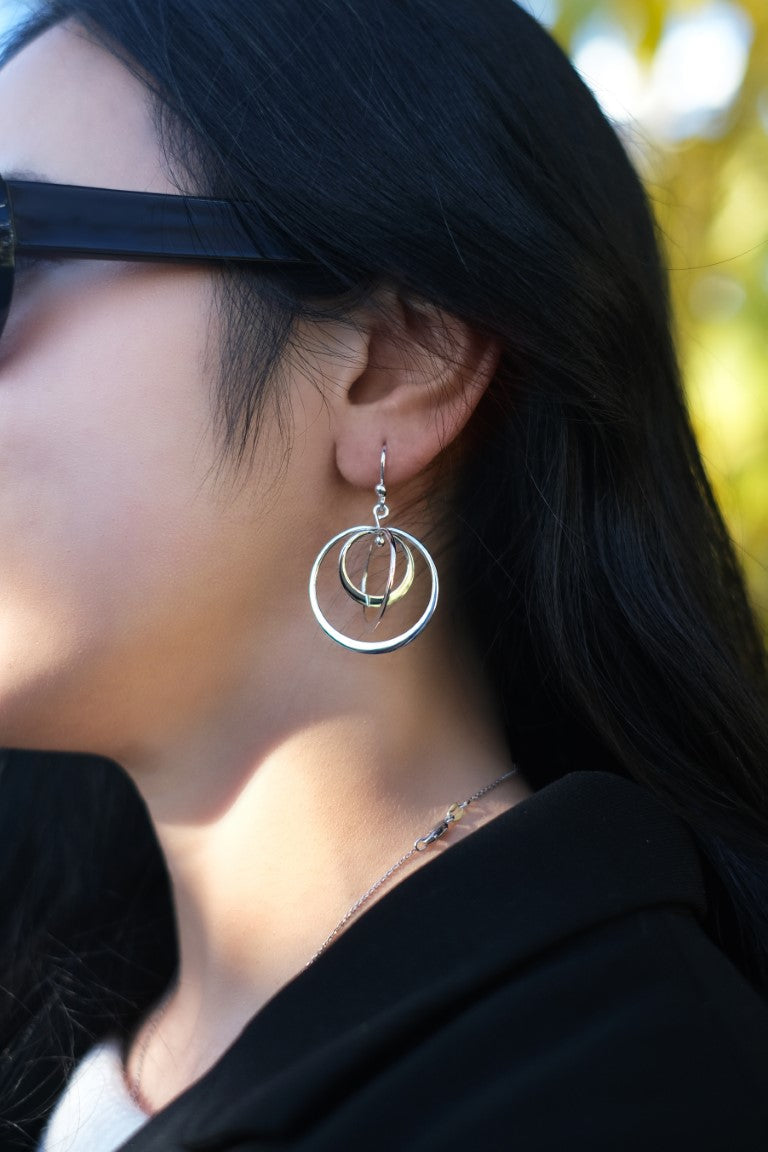 Close-up of a person wearing a Sterling Silver Spinning Hoop Drop Earring with a blurred background