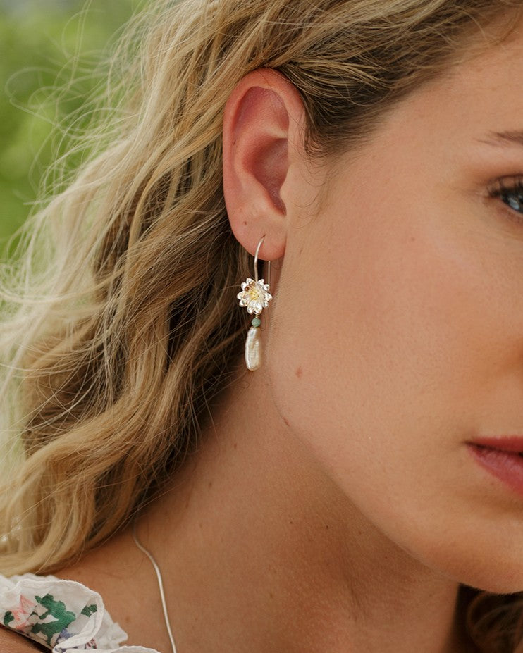 Close-up of a woman wearing a floral earring with a blurred natural background