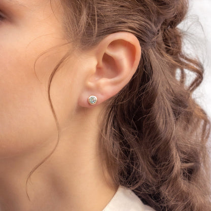 Close-up of a person wearing a Sterling Silver Topaz earring with Gold Detail Studs with a blurred background