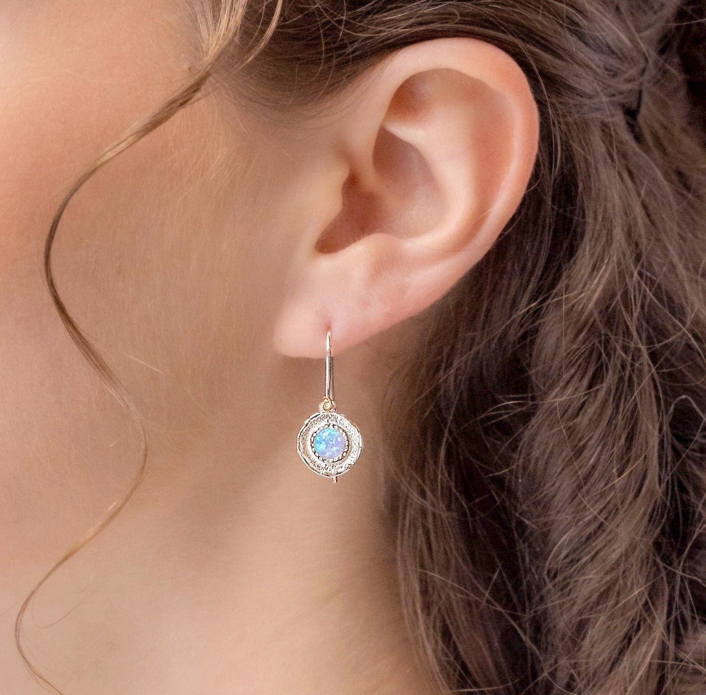 Close-up of an ear wearing a Sterling Silver Blue Opalite Hook Earring, with wavy hair in the background.
