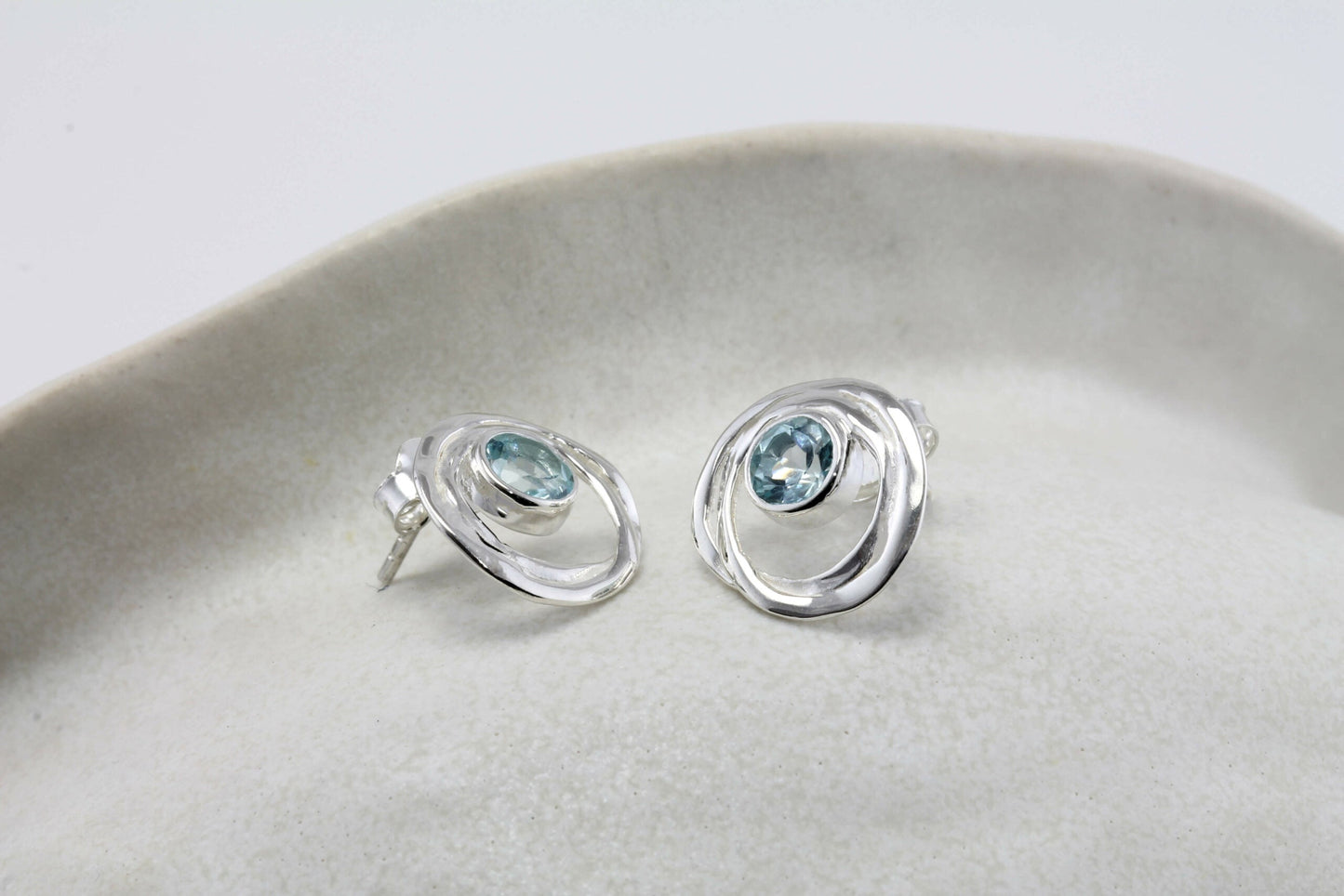Sterling Silver Blue Topaz Loop Studs on a light gray surface