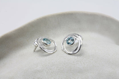 Sterling Silver Blue Topaz Loop Studs on a light gray surface