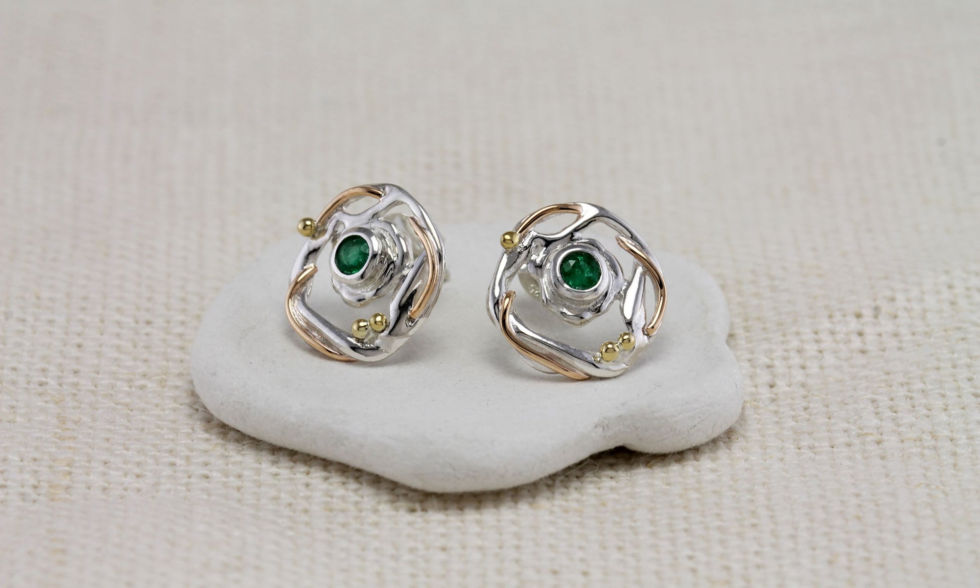 Sterling Silver Circular Mixed Metal Round Emerald Stud Earrings on a white stone