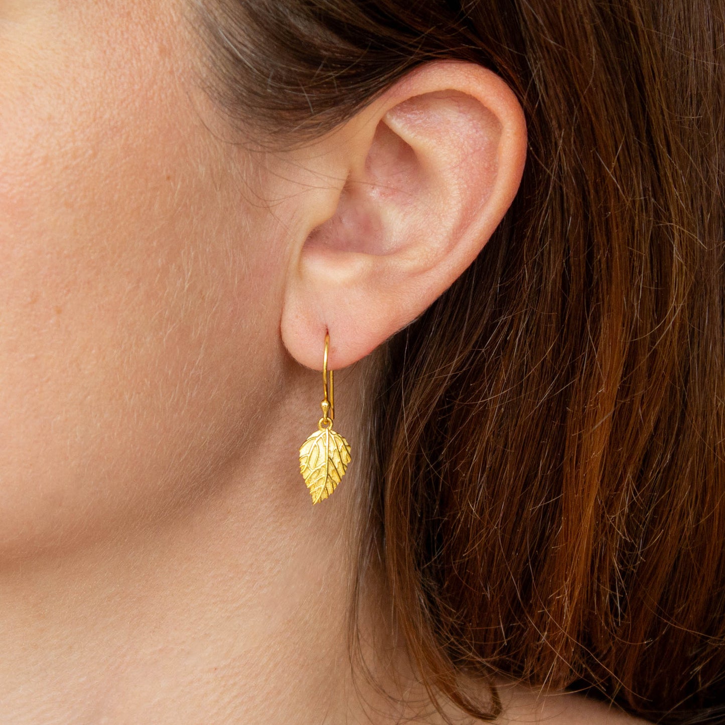 Sterling Silver Textured Leaf 18 carat Gold Vermeil earring worn by a person with brown hair.