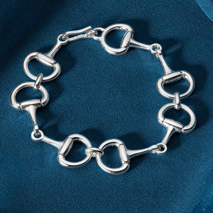 Silver bracelet with horse bit links on a blue fabric background