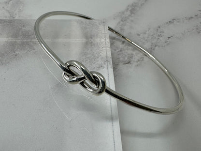 Silver bracelet with a knot design on a marble surface