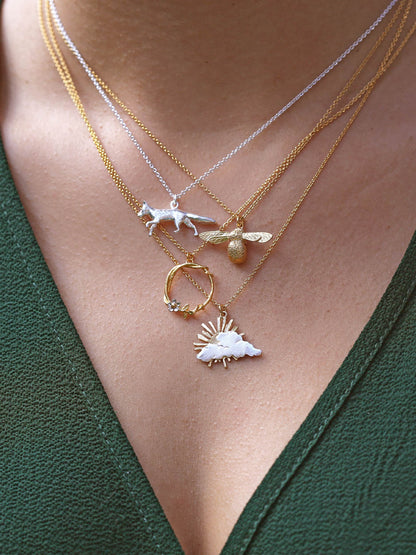 Three necklaces with various pendants on a person wearing a green top.