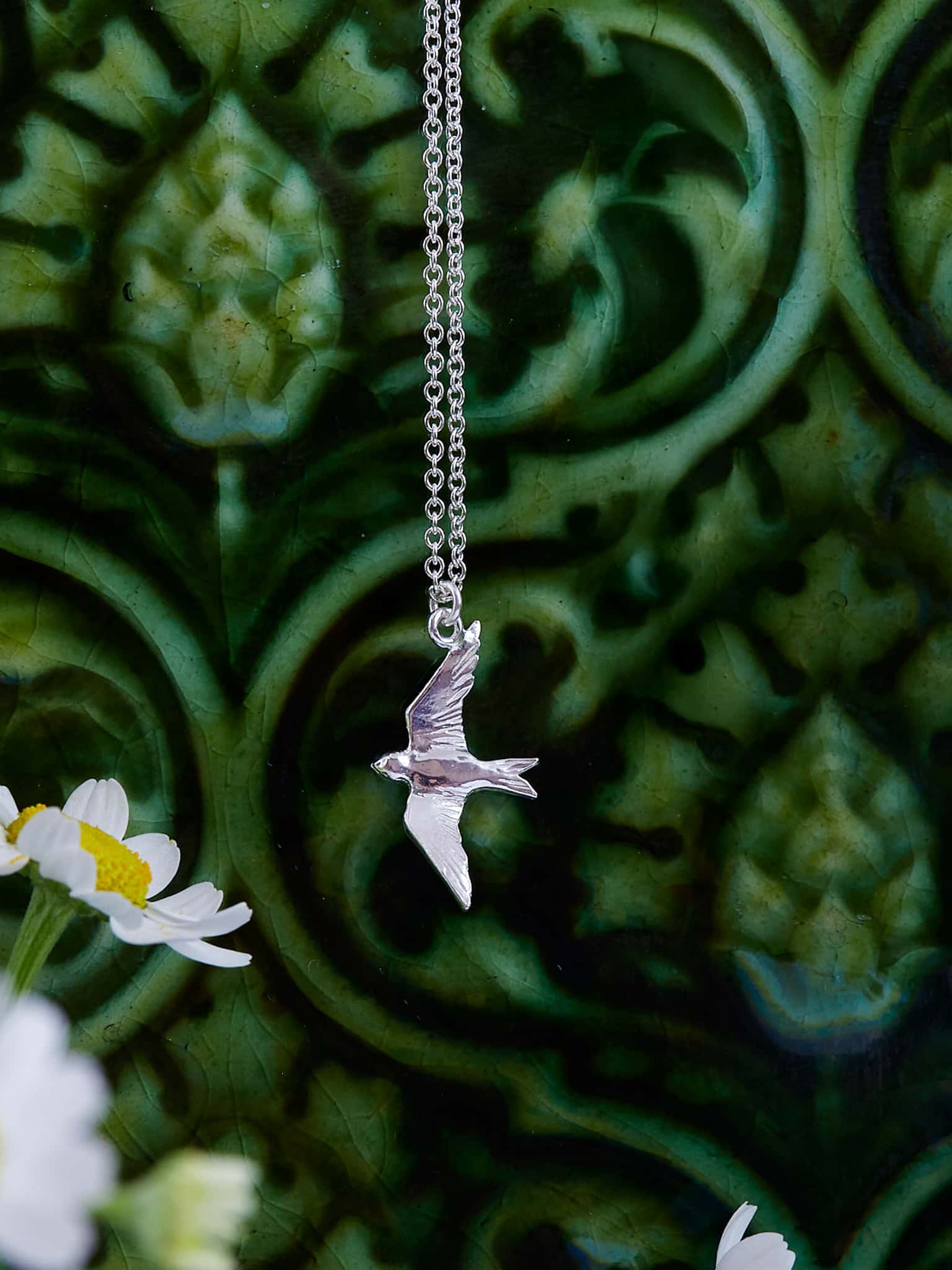 Alex Monroe Sterling Silver Flying Swallow Necklace against a green floral background