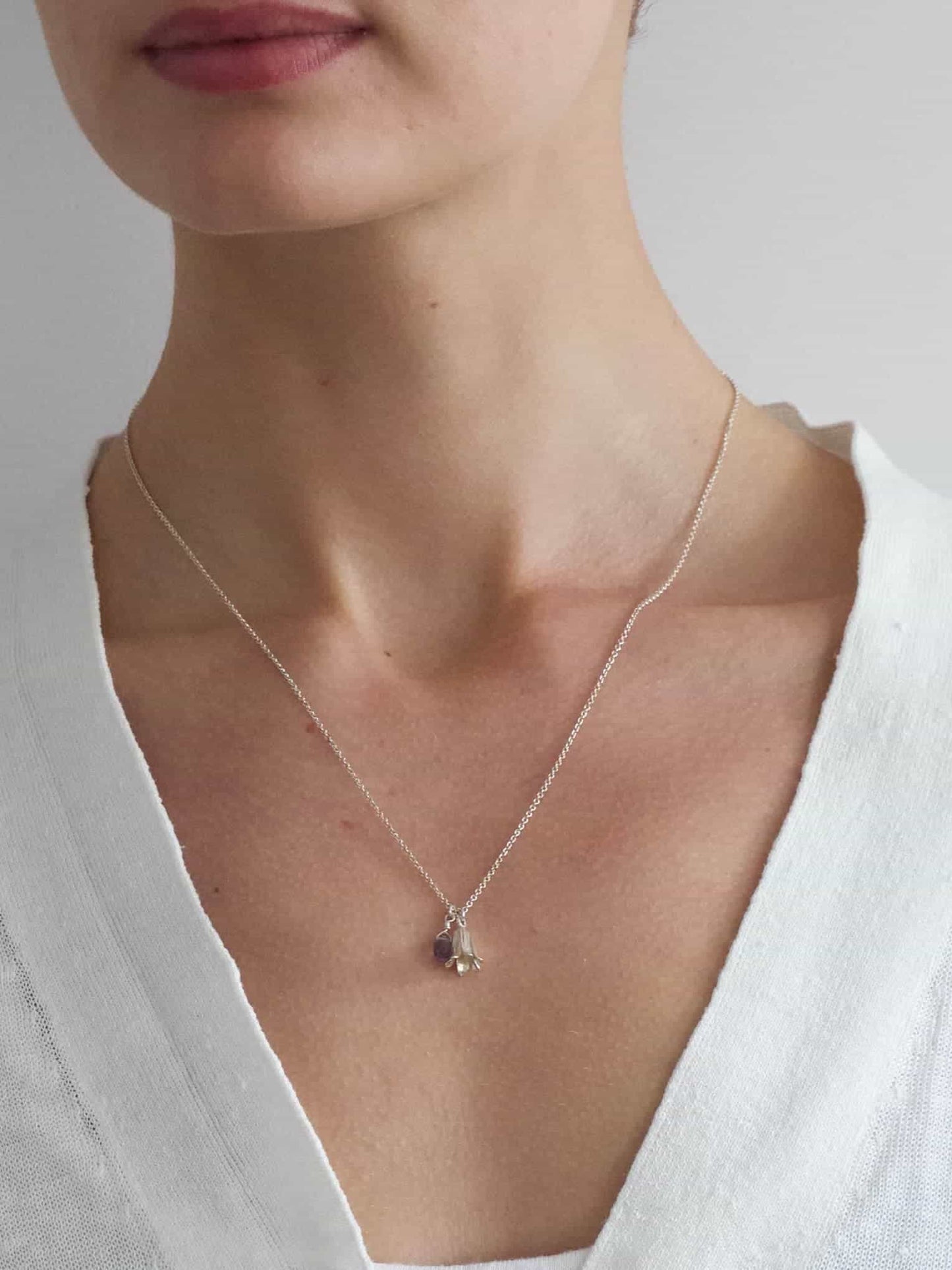 Model in a white top wearing an Alex Monroe Sterling Silver Little Bluebell Necklace With Blue Iolite Stone