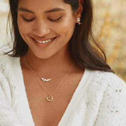 Woman wearing gold necklaces and earrings with a blurred natural background
