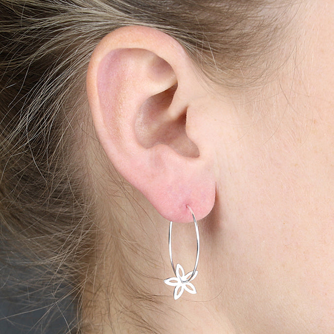 Medium-Sized Sterling Silver Simple Flower Charm Hoop Earring worn by a person.