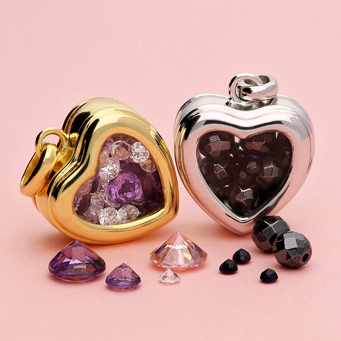 Two heart-shaped jewelry pendants with gemstones on a pink background