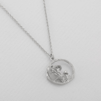 Silver necklace with a circular pendant on a light gray background