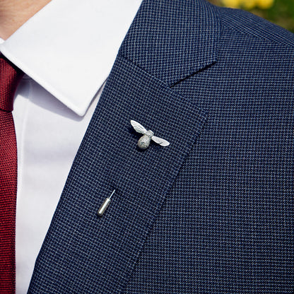 Navy blazer with a silver bee pin on a blurred outdoor background