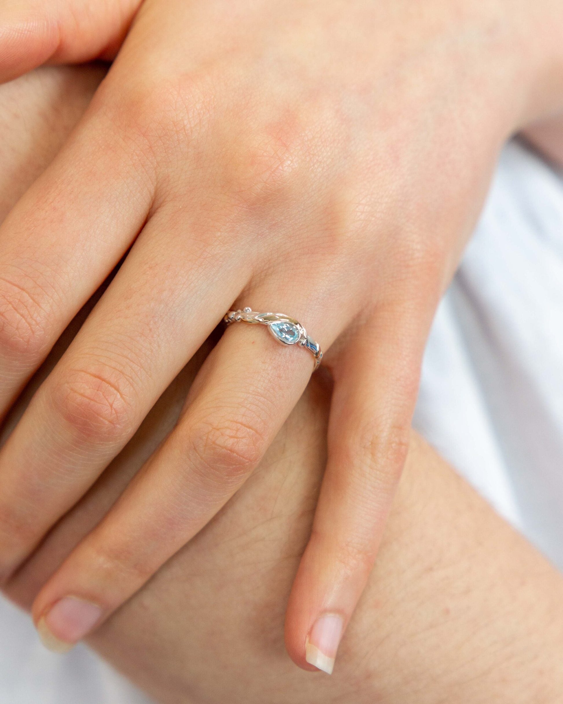 Close-up of a hand wearing a silver ring with a blue gemstone.