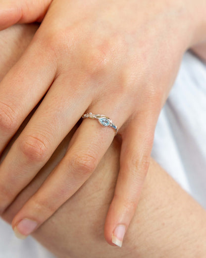 Close-up of a hand wearing a silver ring with a blue gemstone.