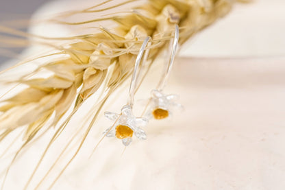 Silver earrings with orange stones on a light fabric background