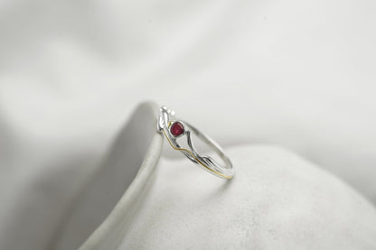 Silver ring with a red gemstone on a white background