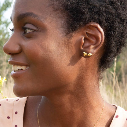 Woman wearing gold earrings outdoors with a blurred natural background